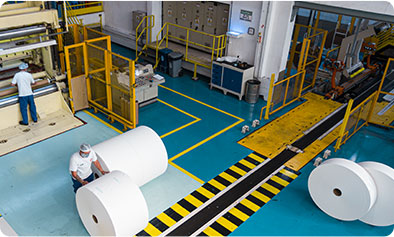 Funcionários manuseando bobinas de papel na fábrica da Celupa